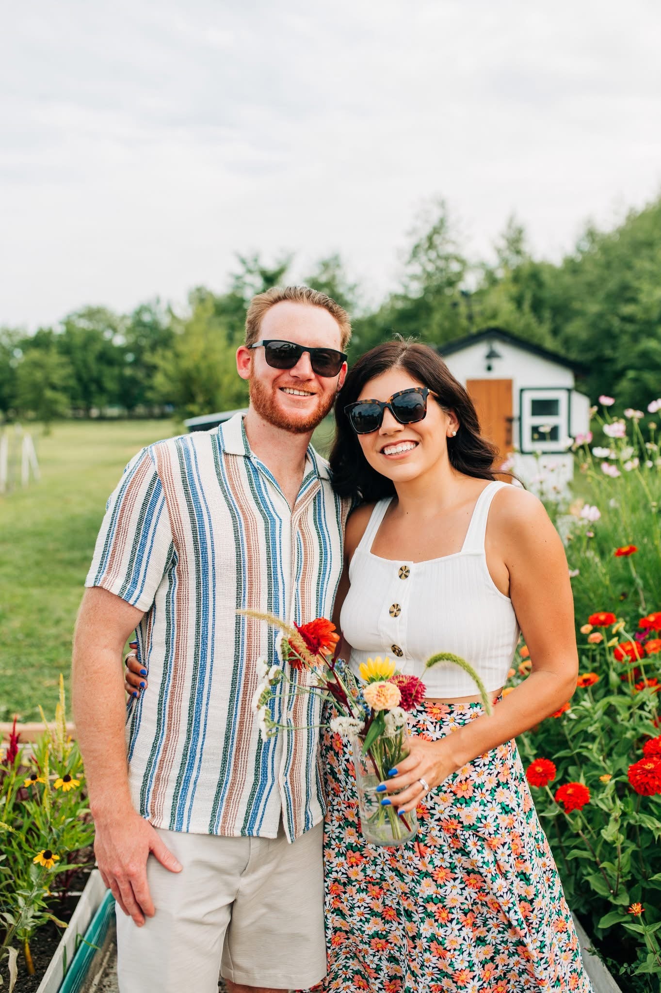 couple picking flowers outside of columbus ohio in the garden with a chicken coop background